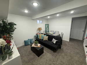 Living room featuring dark carpet and a textured ceiling