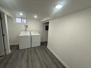 Laundry area featuring dark hardwood / wood-style floors, washing machine and dryer, and a textured ceiling