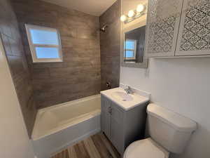 Full bathroom with hardwood / wood-style floors, vanity, toilet, and tiled shower / bath