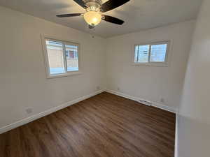 Empty room with dark hardwood / wood-style floors and ceiling fan