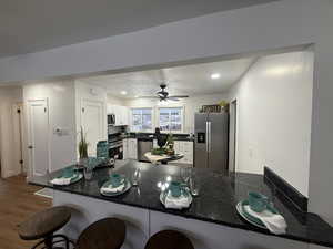 Kitchen with kitchen peninsula, appliances with stainless steel finishes, a breakfast bar, ceiling fan, and white cabinetry