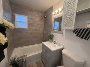 Full bathroom with vanity, hardwood / wood-style flooring, toilet, and tiled shower / bath