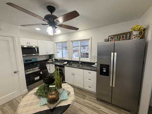 Kitchen with ceiling fan, sink, light hardwood / wood-style floors, white cabinets, and appliances with stainless steel finishes