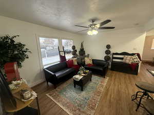 Living room featuring ceiling fan, wood-type flooring, and a textured ceiling