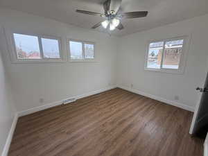 Empty room with ceiling fan and dark hardwood / wood-style floors