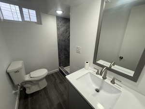 Bathroom with walk in shower, hardwood / wood-style floors, vanity, and toilet