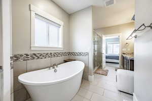 Bathroom with tile patterned flooring, separate shower and tub, and tile walls