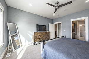 Carpeted bedroom with ceiling fan and ensuite bath