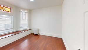 Empty room with dark hardwood / wood-style floors and radiator