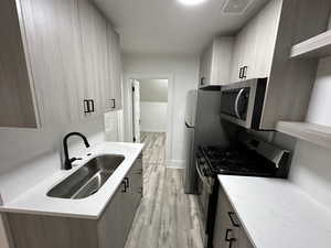 Kitchen featuring light brown cabinetry, sink, stainless steel appliances, and light hardwood / wood-style floors