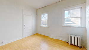 Empty room with hardwood / wood-style floors and radiator