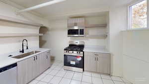 Kitchen with appliances with stainless steel finishes, light brown cabinets, light tile patterned floors, and sink