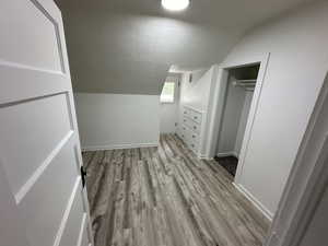 Bonus room with light wood-type flooring and vaulted ceiling