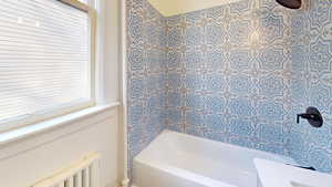 Bathroom with radiator heating unit and tiled shower / bath combo