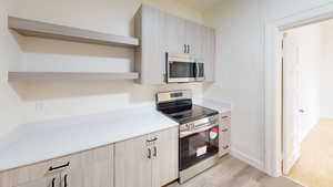 Kitchen with light hardwood / wood-style floors, stainless steel appliances, and light brown cabinets