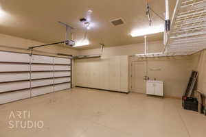 Garage featuring a garage door opener, and lots of storage.  Built in Cabinets and overhead racks.