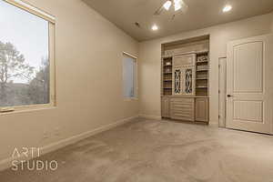 Guest bedroom with carpet flooring and ceiling fan and built in cabinetry