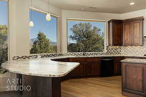 Kitchen featuring decorative light fixtures, decorative backsplash, kitchen peninsula, a mountain view, and light hardwood flooring.