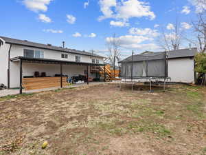 View of yard with a trampoline and a deck