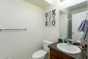 Bathroom featuring vanity, toilet, and a shower with door