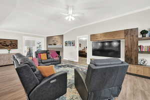 Living room featuring light wood-type flooring, ceiling fan, and crown molding