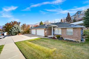 Ranch-style house featuring a mountain view, a front lawn, and a garage