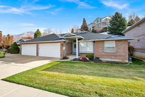 Single story home with a mountain view, a garage, and a front lawn