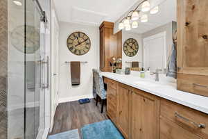 Bathroom featuring hardwood / wood-style flooring, vanity, and an enclosed shower