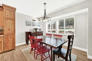 Dining area with light hardwood / wood-style floors and a notable chandelier