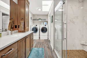 Clothes washing area featuring separate washer and dryer, hardwood / wood-style flooring, and sink