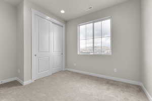 Unfurnished bedroom with light colored carpet and a closet