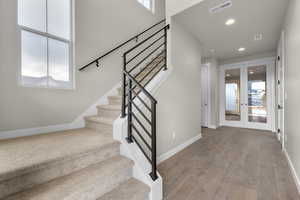Staircase featuring hardwood / wood-style floors and french doors