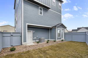 Back of property featuring cooling unit and a lawn