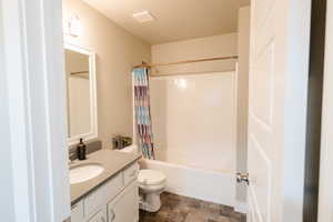 Full bathroom with a textured ceiling, vanity, shower / tub combo, and toilet