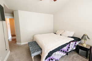 Carpeted bedroom featuring ceiling fan and lofted ceiling