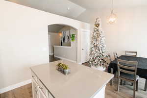 Kitchen with pendant lighting, white cabinets, vaulted ceiling, a notable chandelier, and light hardwood / wood-style floors