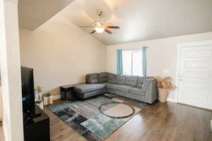 Living room with ceiling fan, wood-type flooring, and vaulted ceiling