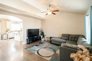 Living room with ceiling fan, lofted ceiling, sink, and light hardwood / wood-style flooring