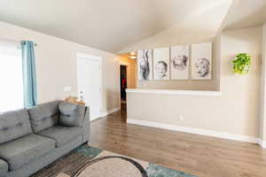 Living room with lofted ceiling and hardwood / wood-style flooring