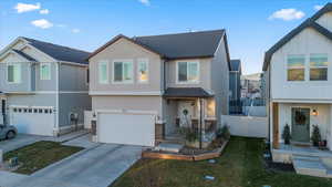 View of front of home with board and batten siding, stucco siding, roof with shingles, an attached garage, and concrete driveway