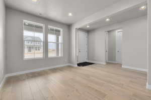 Foyer entrance with light hardwood / wood-style floors and a textured ceiling