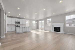 Unfurnished living room featuring a notable chandelier, sink, and light hardwood / wood-style flooring