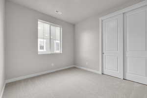 Unfurnished bedroom featuring light colored carpet and a closet