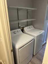 Clothes washing area with hardwood / wood-style flooring and washing machine and clothes dryer