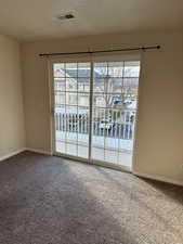 Empty room with carpet, plenty of natural light, and a textured ceiling