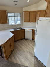 Kitchen featuring vaulted ceiling, light hardwood / wood-style flooring, white appliances, and sink