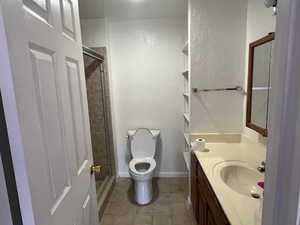 Bathroom with tile patterned flooring, vanity, an enclosed shower, and toilet