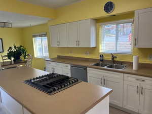 Kitchen with white cabinets, a center island, sink, and appliances with stainless steel finishes