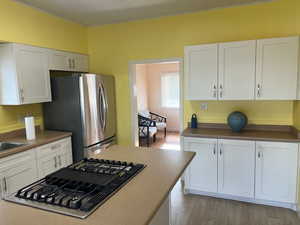 Kitchen with white cabinets, stainless steel appliances, and light hardwood / wood-style floors