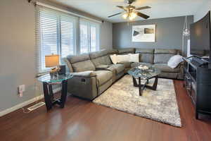 Living room with ceiling fan and dark wood-type flooring